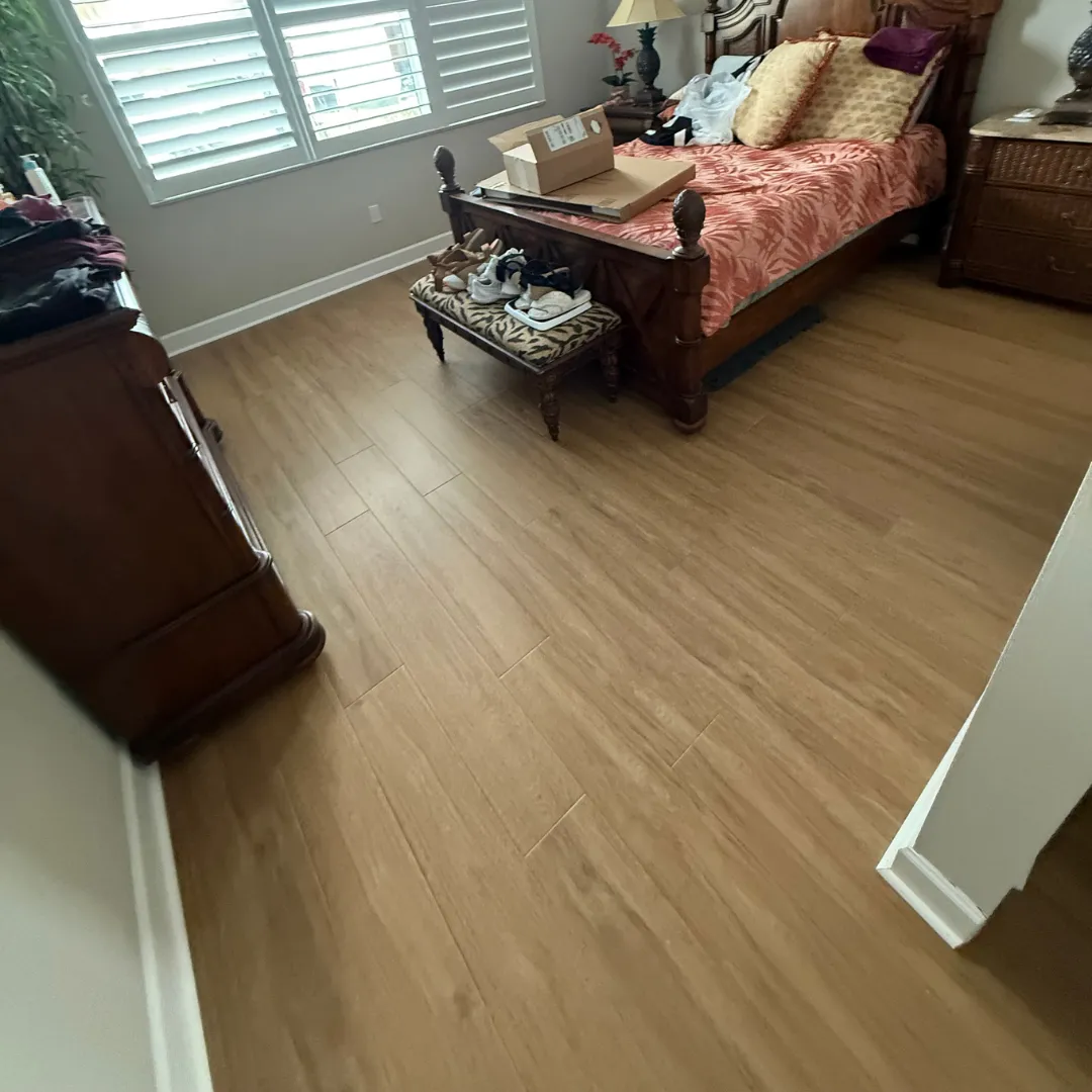 Bamboo plank flooring installation in furnished bedroom