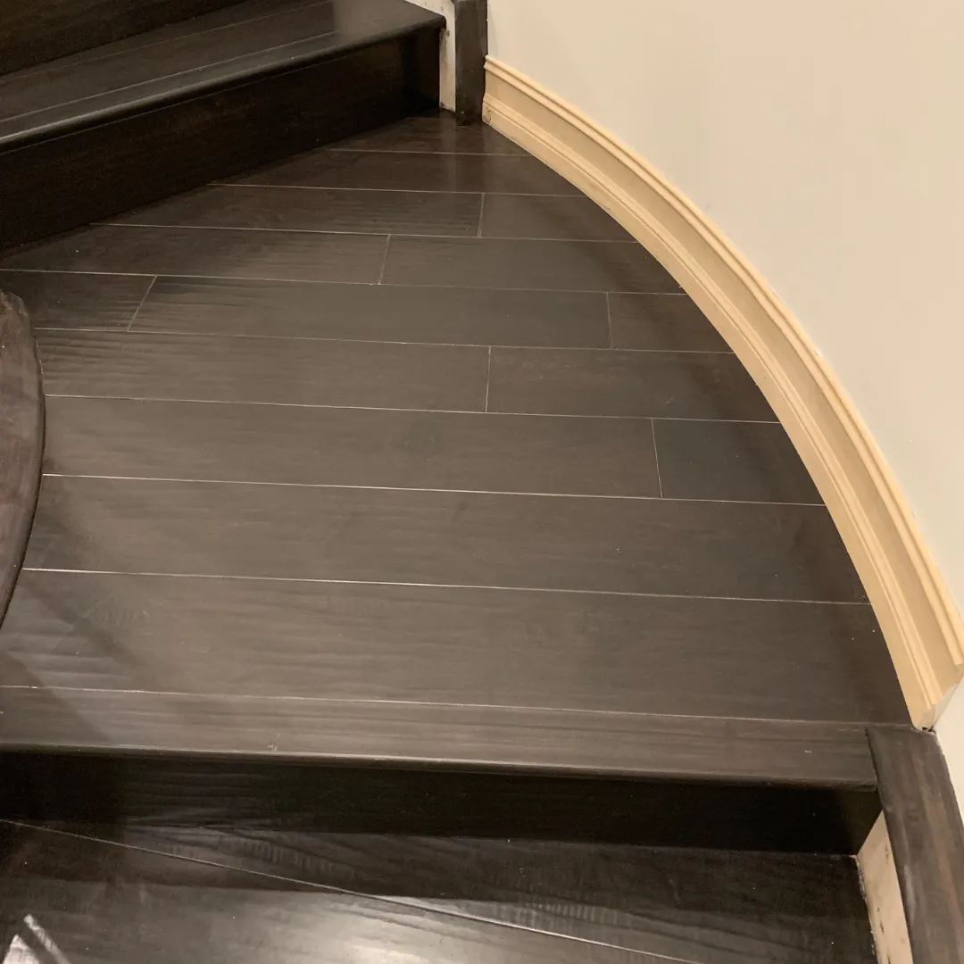 Dark wood-look luxury vinyl plank flooring on curved stair landing in Florida home